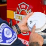 firefighter pushing the test button on a smoke alarm