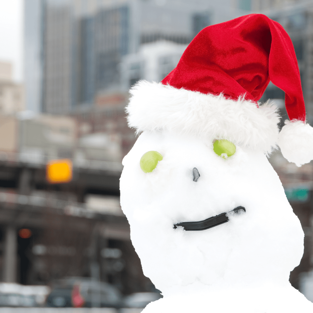 Picture of a snowperson wearing a santa hat with seattle blurred in the background