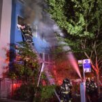 Firefighter on a ladder work to rescue residents from apartment complex on fire