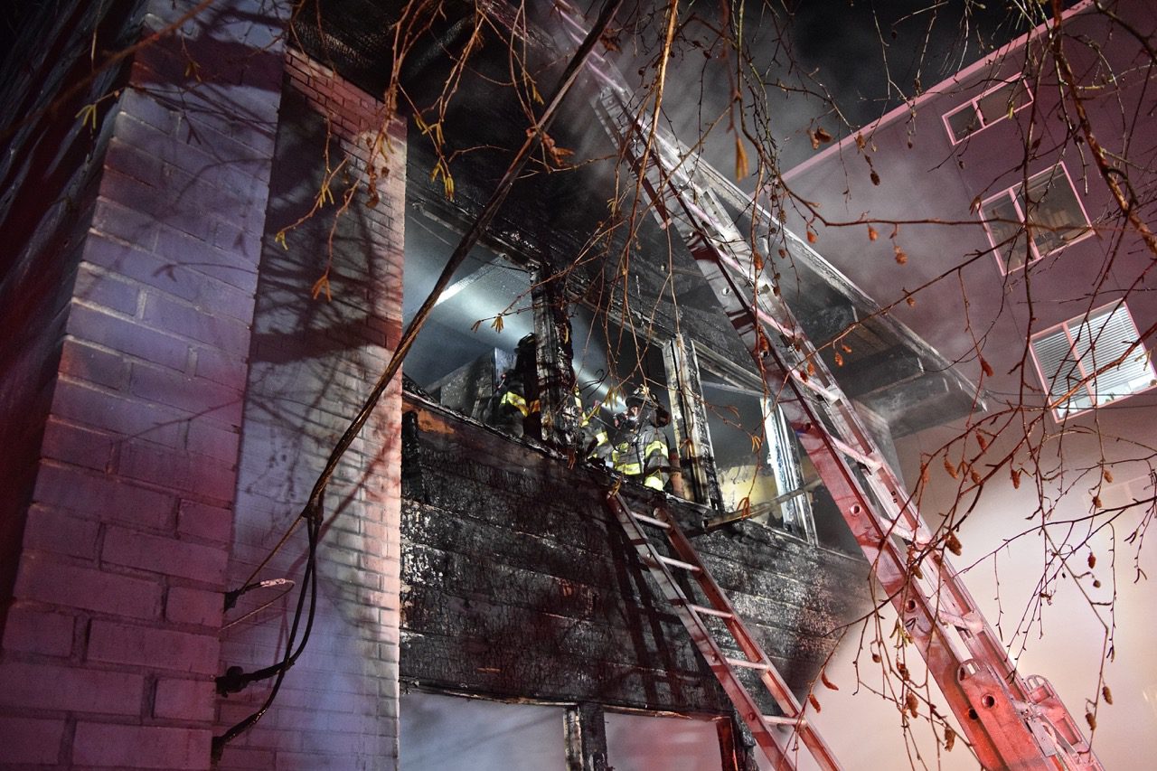 Firefighters stand in burned apartment unit.