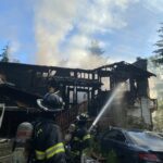 Firefighters put water on a house fire.