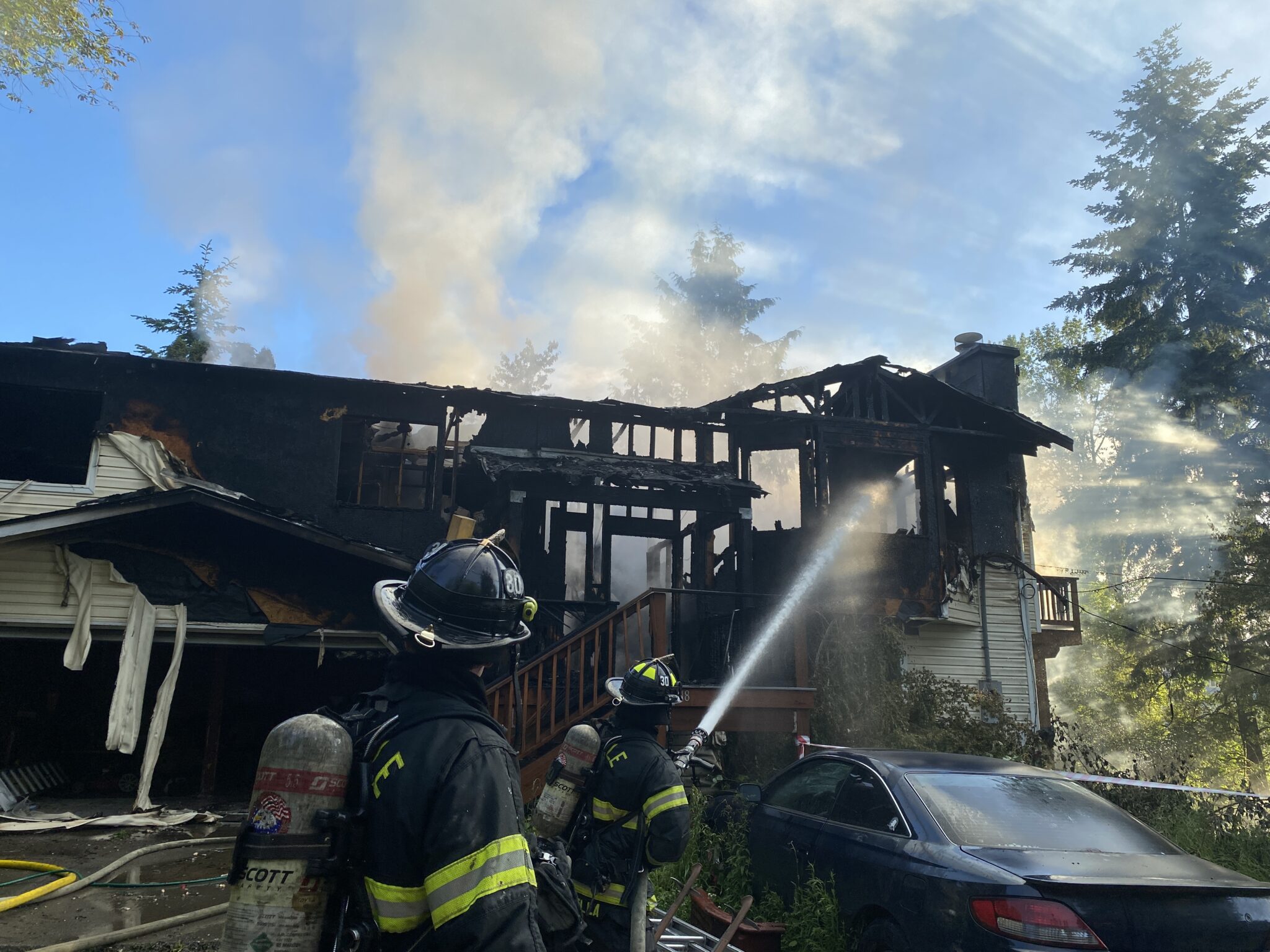 Firefighters put water on a house fire.