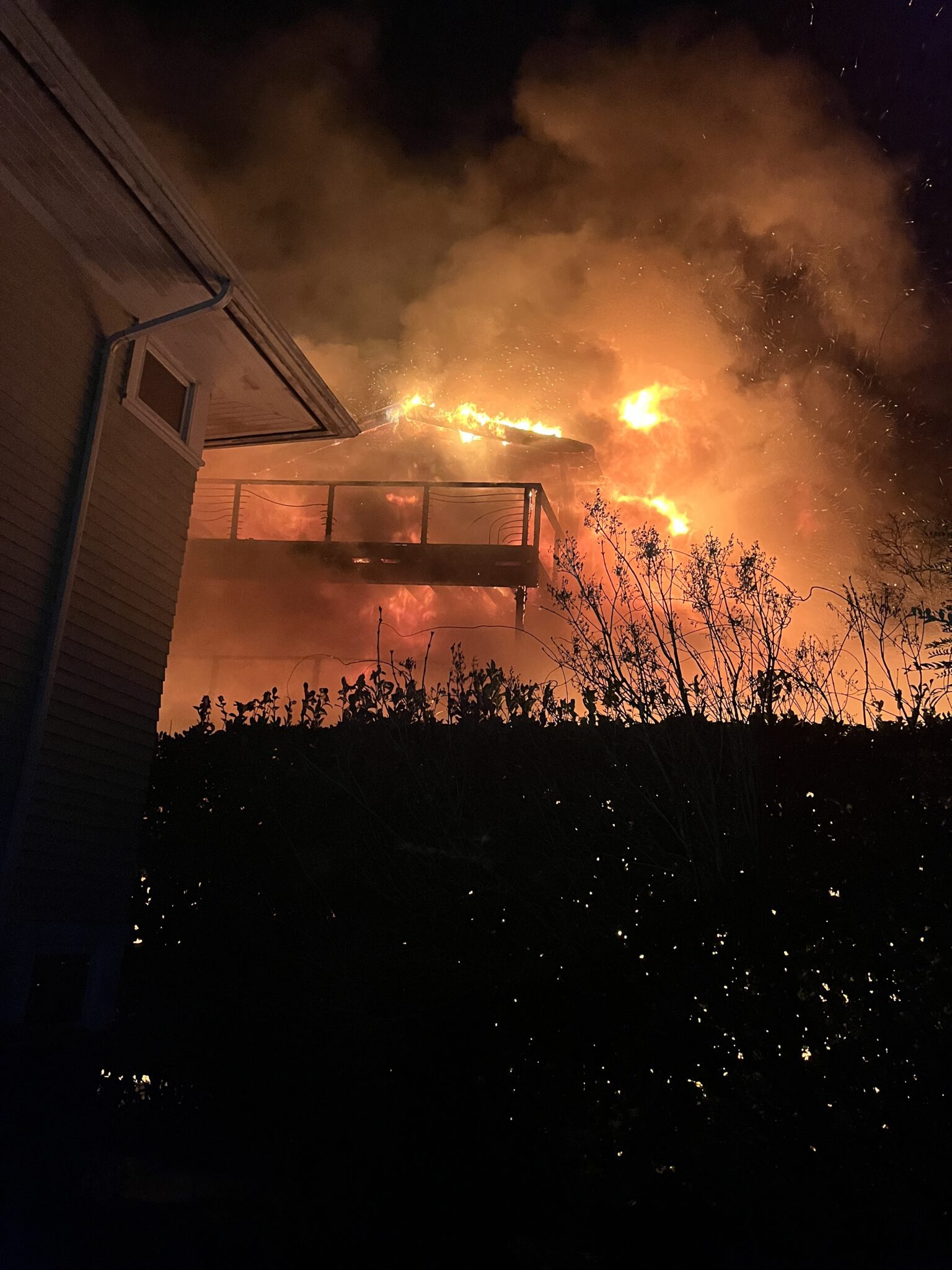 Flames coming from the deck and second floor of a home.