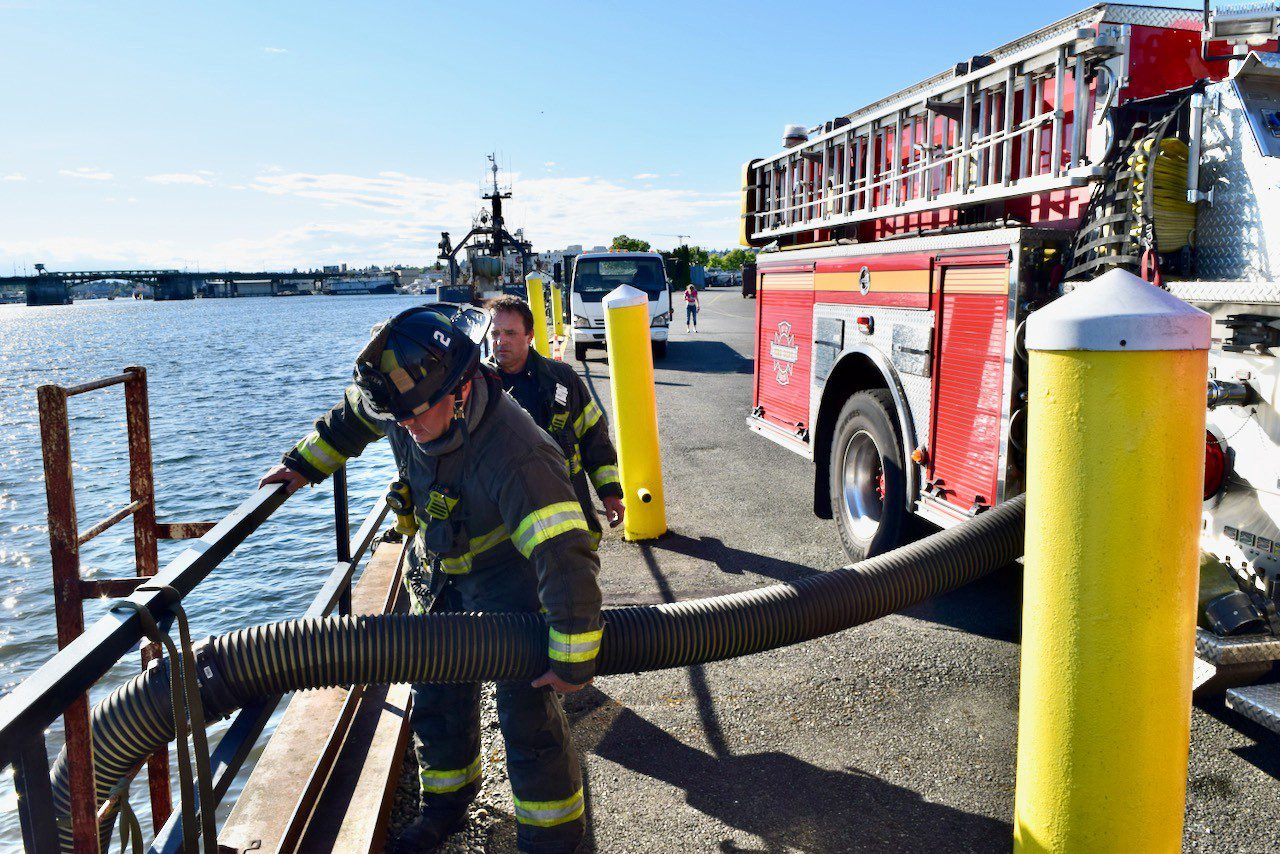 Firefighters pump water from ship canal.