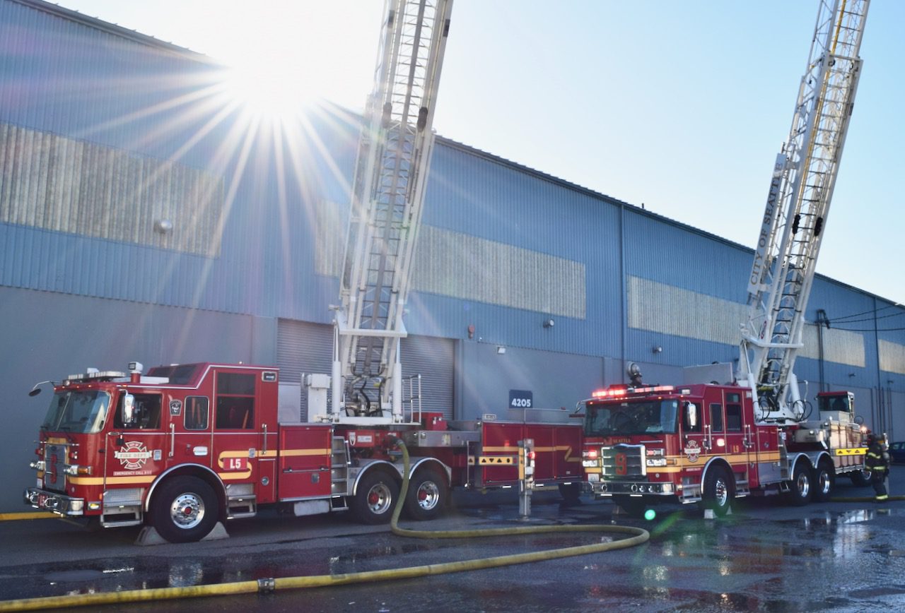 Two ladder trucks with aerial ladders fully extended.