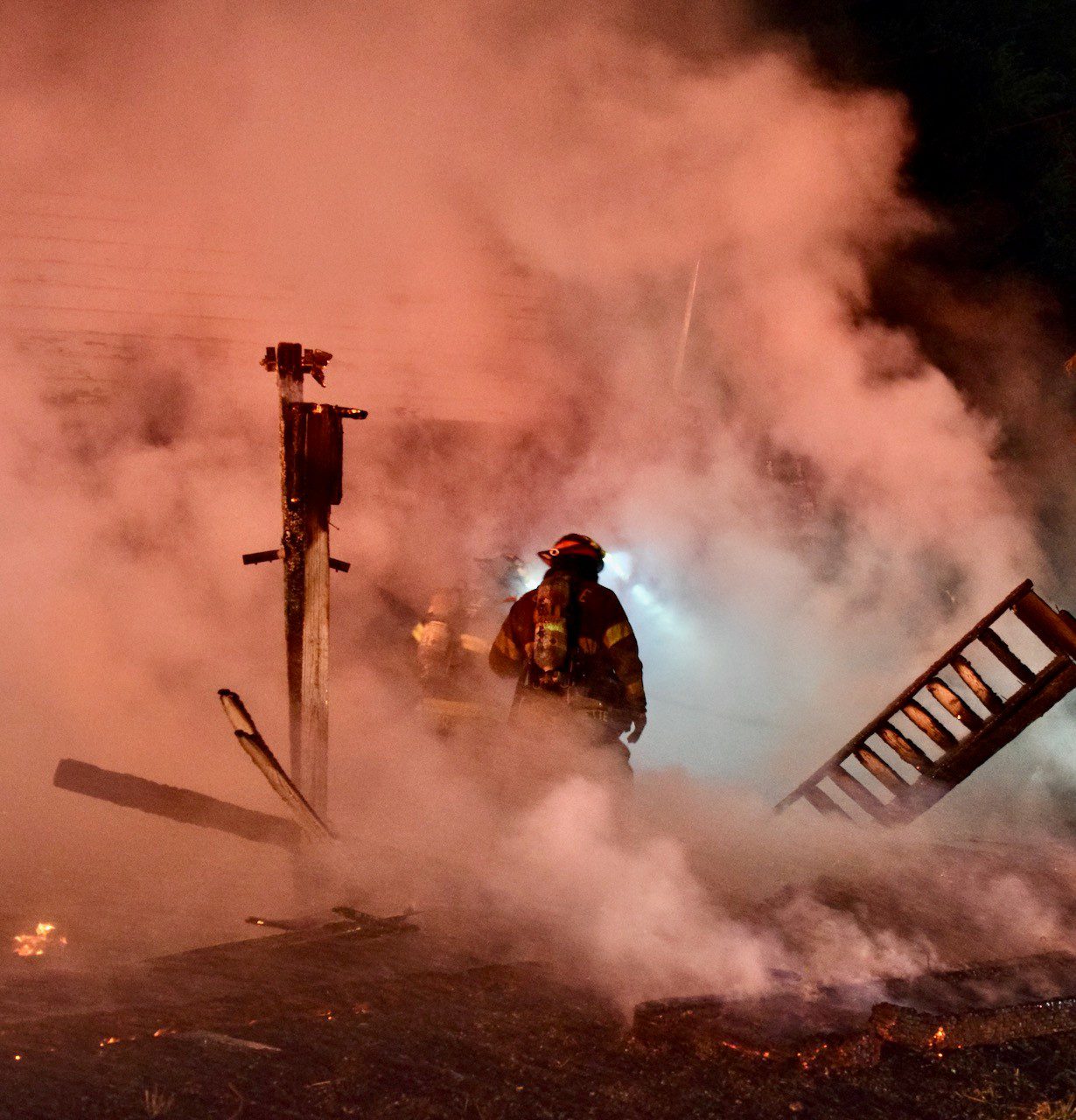 Firefighters evaluate deck collapse, surrounded by smoke.