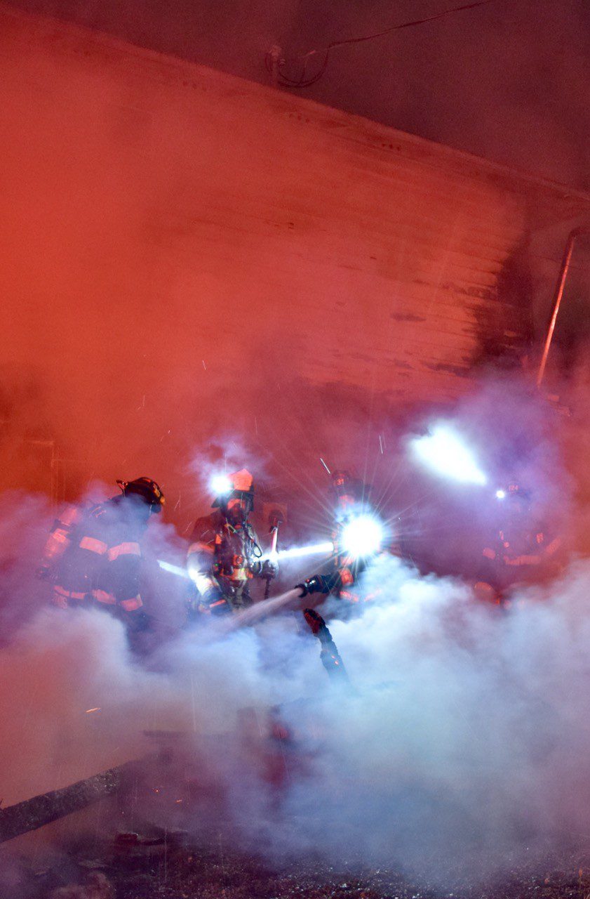 Firefighters in smoke with headlamps lit.