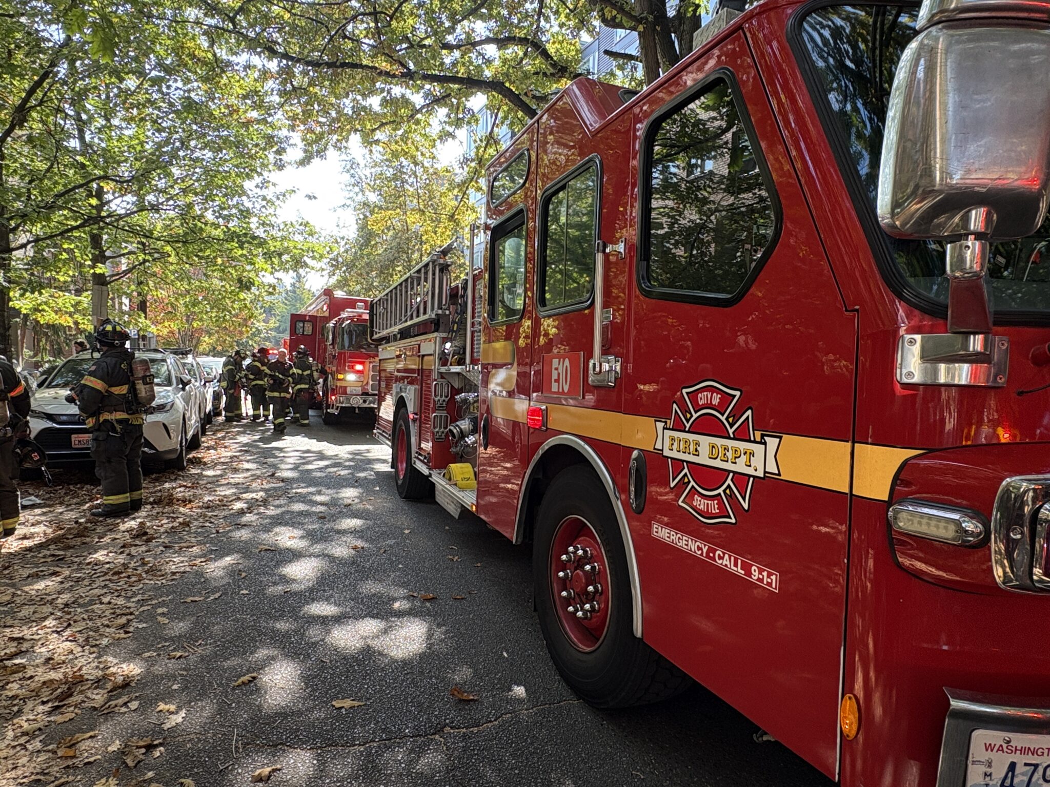 Firefighters huddle near fire engine.